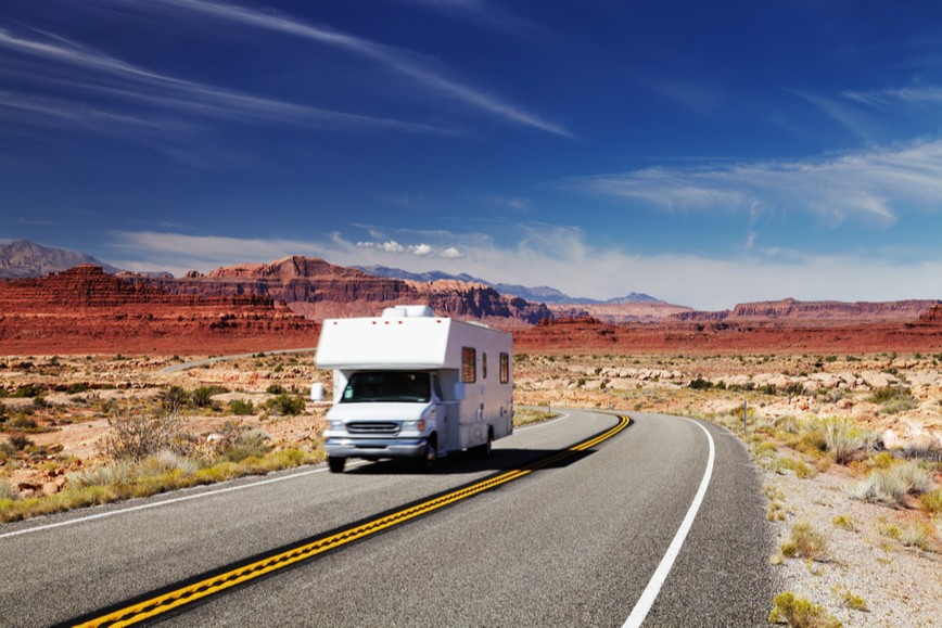 An RV driving through a scenic desert vista